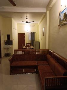 a living room with brown couches and a dining room at Godiva Homestay in Cochin