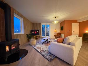 een woonkamer met een witte bank en een open haard bij Le lofty in Stoumont