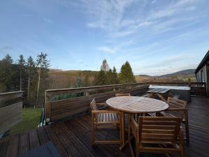 een houten terras met een tafel en stoelen erop bij Le lofty in Stoumont