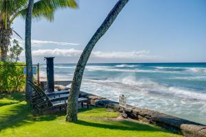 een bank naast de oceaan met palmbomen bij Private Balcony! Lahaina Retreat with Ocean Access in Honokowai