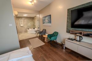 a living room with a large television and a bathroom at Hotel Mediteraneo Garni in Novi Sad