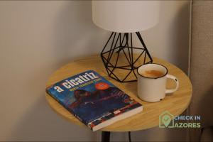een boek en een kopje koffie op een tafel bij Cantinho da Bea I in Angra do Heroísmo