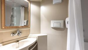 a white bathroom with a sink and a mirror at Premiere Classe Valenciennes Ouest Petite Foret in Petite Forêt