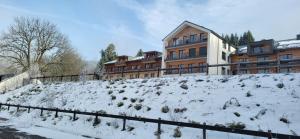 a snow covered hill in front of a building at Apartmán Šumavský Buk 14 Brčálník in Hojsova Stráž