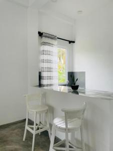 een keuken met twee witte krukken en een aanrecht bij Villa C & C Thalpe in Talpe