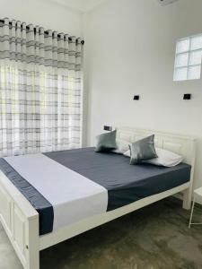 een witte slaapkamer met een groot bed met blauwe lakens bij Villa C & C Thalpe in Talpe
