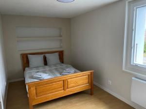 a bedroom with a bed with a wooden frame and a window at Appartement 3 Pièces, Neuvecelle in Neuvecelle