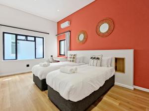 two beds in a room with an orange wall at Palm Paradise - Boutique Guest House in Cape Town +62 photos