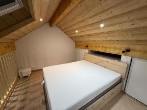 een kleine kamer met een bed in een houten plafond bij Le Crystalia in Prabert