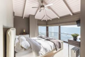 ein Schlafzimmer mit einem weißen Bett mit Deckenventilator in der Unterkunft Deluxe Villa by White Hills Outdoor Hot Tub in Arachova