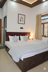 een slaapkamer met een groot bed met witte lakens bij Monishka Palace in Faizābād