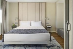 1 Schlafzimmer mit einem großen weißen Bett und 2 Tischen in der Unterkunft NH Madrid Ventas in Madrid