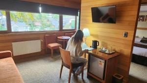 a woman sitting at a desk in a hotel room at Puerto Chico Hotel in Puerto Varas