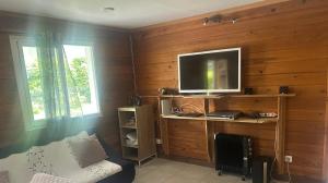 a living room with a tv on a wooden wall at Ti' case la plaine in La Plaine des Palmistes