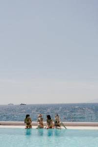 a group of women sitting in a swimming pool next to the ocean at Maya Beach Resort in Massa Lubrense