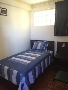 a bedroom with a bed with a blue and white striped blanket at Residencial Alta Vista in La Paz