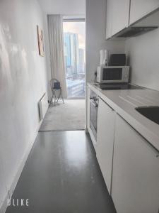 a kitchen with white cabinets and a microwave and a window at Birmingham Central NewStreet 1Bed in Birmingham