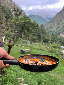 una persona che tiene in mano una padella con una griglia di Royal Mount a Kasol