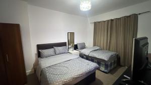 a bedroom with two beds and a tv in it at Greenwich Homestay in London