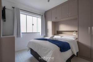 ein Schlafzimmer mit einem großen Bett und einem Fenster in der Unterkunft Apto 2Q c/ churrasq. no centro - Bombinhas CAA103 in Bombinhas