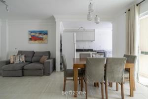 ein Esszimmer und ein Wohnzimmer mit Tisch und Stühlen in der Unterkunft Apto 2Q c/ churrasq. no centro - Bombinhas CAA103 in Bombinhas