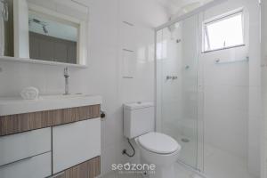 ein weißes Badezimmer mit Toilette und Dusche in der Unterkunft Apto 2Q c/ churrasq. no centro - Bombinhas CAA103 in Bombinhas + 15 Fotos