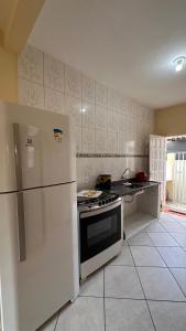 een keuken met een witte koelkast en een fornuis bij Casa Guriri in São Mateus