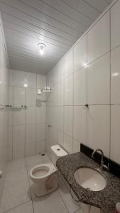een witte badkamer met een toilet en een wastafel bij Casa Guriri in São Mateus