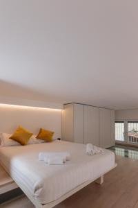 une chambre avec un grand lit blanc avec des oreillers jaunes dans l'établissement ArtStay - Exclusive Apt Near Metro M1, AC, Parking, à Milan