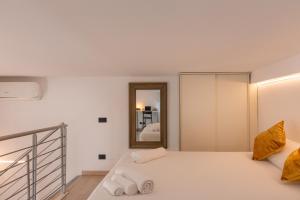 une chambre blanche avec un lit et un miroir dans l'établissement ArtStay - Exclusive Apt Near Metro M1, AC, Parking, à Milan