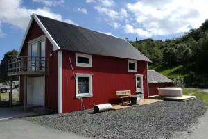 een rode schuur met een balkon en een bankje bij Larsen Rorbu Lofoten in Napp