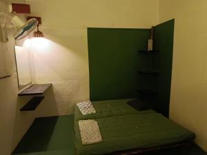 een kleine groene kamer met een bed en een tafel bij PARV Farms in Belgaum +4 foto's