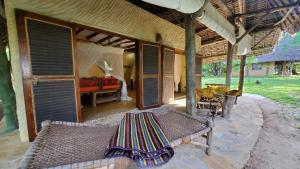 eine Außenterrasse mit Bank und Bett in der Unterkunft Eco Shamba Kilole Lodge in Utende