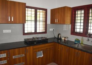 een keuken met houten kasten en zwarte aanrechtbladen bij MeadowView Cottage Marari in Mararikulam