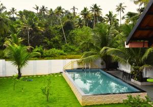 een zwembad in een tuin naast een huis bij MeadowView Cottage Marari in Mararikulam