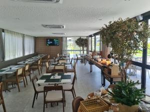 een eetkamer met tafels en stoelen en ramen bij Beach Class Summer in Porto De Galinhas