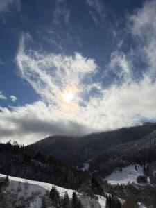 a view of a snow covered mountain with the sun in the sky at Mitarbi Silence - cozy holiday cottages in mountains in Borjomi