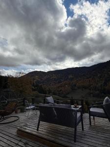 a deck with a bench and a view of the mountains at Mitarbi Silence - cozy holiday cottages in mountains in Borjomi