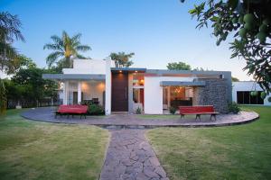 a house with two red benches in front of it at Casa Vida - Arte, Naturaleza y Confort in Santa Cruz de la Sierra
