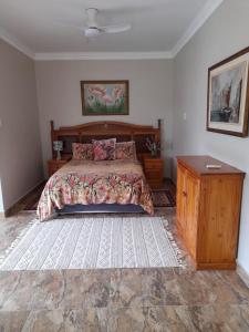 een slaapkamer met een bed en een houten dressoir bij Benguela B&B in Richards Bay