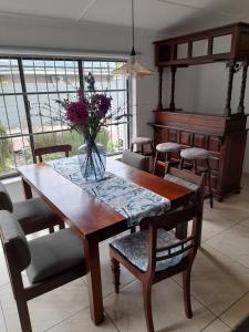 een eettafel met een vaas met bloemen erop bij Benguela B&B in Richards Bay