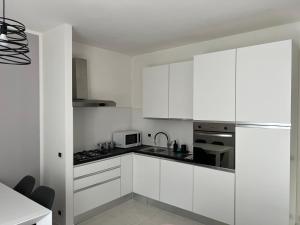 a white kitchen with white cabinets and a microwave at Il Rifugio in Sulmona
