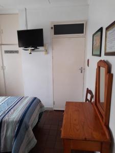 een slaapkamer met een bed, een tafel en een tv bij Benguela B&B in Richards Bay