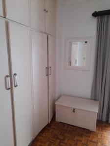 een kamer met witte kasten, een lade en een spiegel bij Benguela B&B in Richards Bay