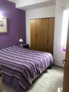 una camera da letto con un letto con una parete viola di Anisados 1 a Las Grutas