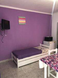 una camera da letto con pareti viola, un letto e una TV di Anisados 1 a Las Grutas