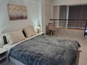 een slaapkamer met een bed, een stoel en een raam bij Konstantinos Loft in Serres