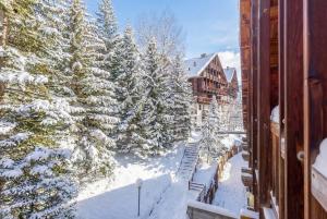 ein Wohnungsbalkon mit Blick auf schneebedeckte Bäume und Gebäude in der Unterkunft Hostdomus-La casa di Luna in Grange Sises