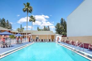 a pool at a hotel with chairs and palm trees at Howard Johnson by Wyndham Ft. Myers FL in Fort Myers