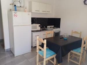 eine Küche mit einem Tisch und einem weißen Kühlschrank in der Unterkunft Departamento NAMASTE I in Carhué